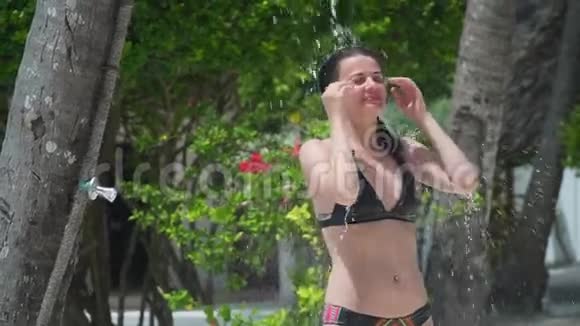 年轻女子在豪华度假村享受热带淋浴视频的预览图