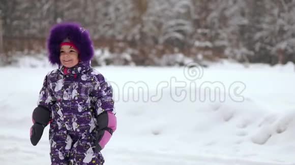 快乐的孩子在冬天的第一场雪中玩耍冬暖夏凉的小男孩穿着温暖的雪服走路玩得开心视频的预览图