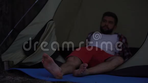 孤独的露营者光着脚躺在帐篷里为孤独而悲伤没有灵魂伴侣视频的预览图