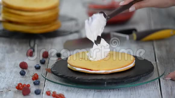 糖果师把奶油涂抹在层蛋糕上用浆果馅做蛋糕的过程视频的预览图