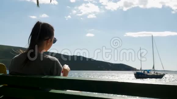女孩坐在海边的长凳上视频的预览图