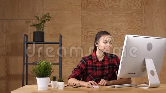 美丽的自由职业者女性在视频会议上与耳机与麦克风和电脑在线交谈视频的预览图