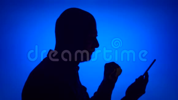 高级男士剪影在蓝色背景上使用移动男的侧脸收到好消息视频的预览图
