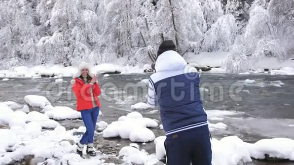 冬天的摄影师在雪的背景下在山河附近拍摄女孩视频的预览图