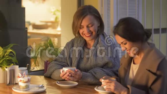 两个姐妹在咖啡馆里放松喝着热咖啡聊天玩得很开心视频的预览图
