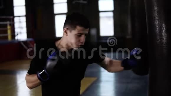 英俊的拳击手在戴黑色手套时打了沉重的袋子运动拳击背景视频的预览图