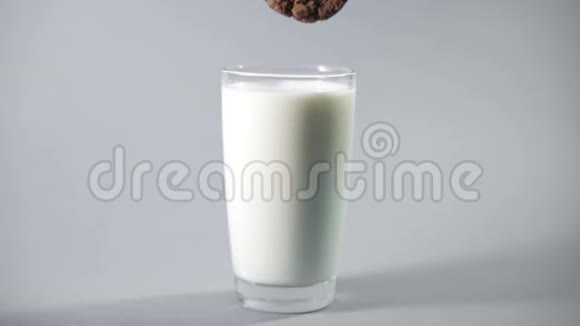 女性手在牛奶中蘸着巧克力饼干慢动作视频的预览图