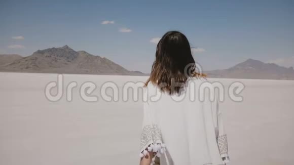 镜头跟随美丽的年轻快乐的自由女人向前奔跑手臂张开飞毛在盐漠湖视频的预览图