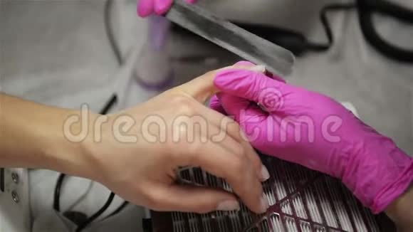 美容师在美容沙龙里为一个美容师磨指甲吧手指指甲处理研磨和抛光视频的预览图