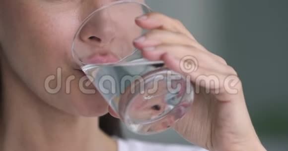 健康的年轻女士拿着玻璃饮用水近距离观看视频的预览图