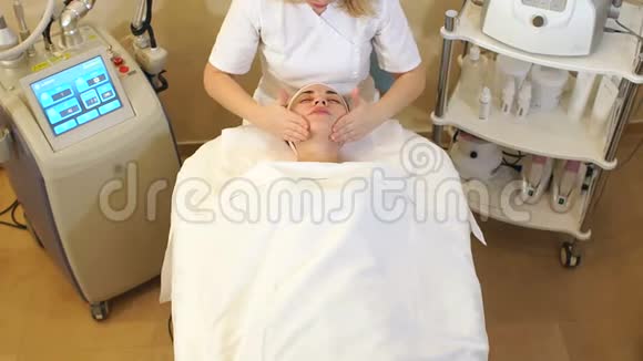 美容师用保湿霜给一个年轻女孩做面部按摩视频的预览图