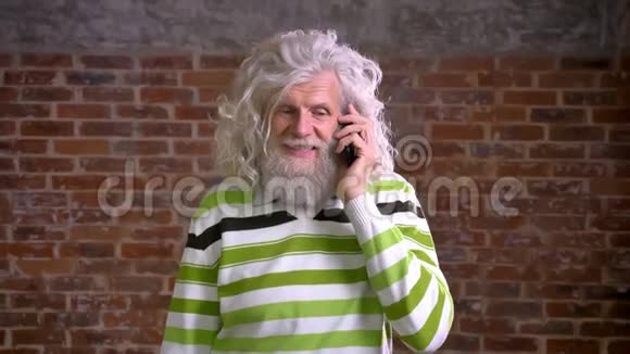 一位留着白发浓密胡须的白种人高级男子挂在电话上面带笑容地说话视频的预览图