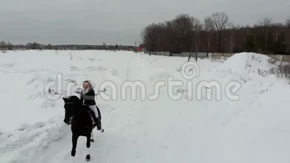 一个年轻的微笑的女人骑着马在雪地上视频的预览图