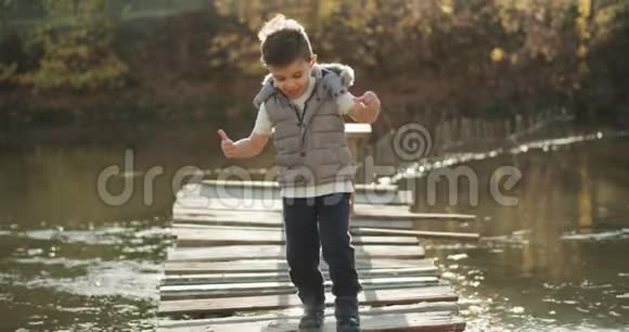 在湖边的桥上走着一个可爱的小男孩4k视频的预览图