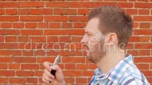 英俊的时尚男士在砖墙上抽着蒸气看着相机慢节奏时尚视频的预览图