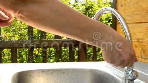 夏日阳光明媚的一天女人在花园的室外自来水中洗手使用干净的水和卫生视频的预览图