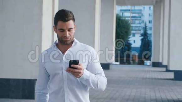 商人在商业区的街道上行走使用手机看上去很成功穿着长胡子的男人视频的预览图