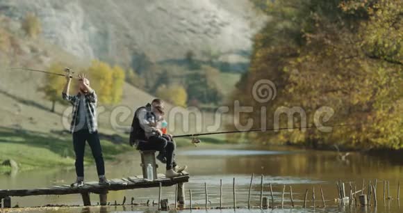 美丽的地方在大自然神奇的湖两个男人和一个小男孩一起钓鱼4k视频的预览图