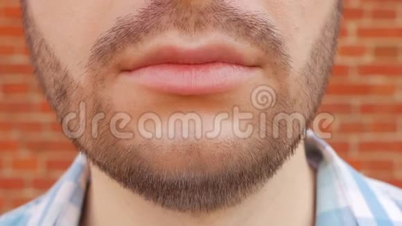 一个留着胡子的人正对着镜头对着砖墙微笑特写镜头脸慢镜头视频的预览图