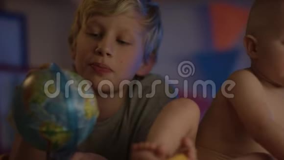 宝宝只是坏坐着玩地球仪和他的兄弟做公司流动相机视频的预览图
