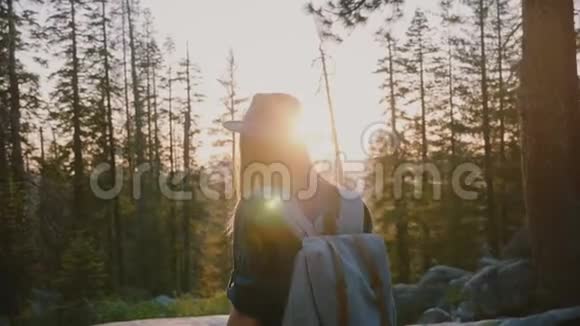 镜头跟随兴奋的旅游女孩在森林深处徒步旅行在日落时步行到令人惊叹的溪流约塞米蒂公园慢动作视频的预览图