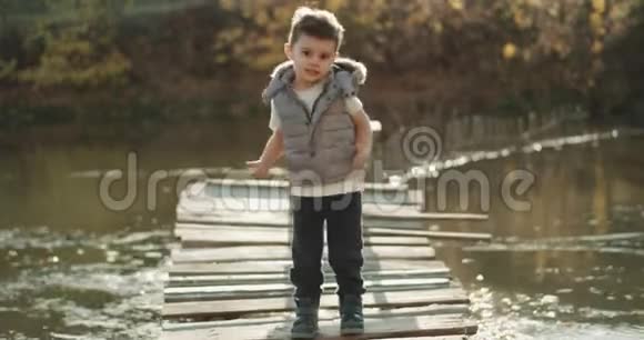 一个有魅力的男孩在镜头前的大自然旁边的湖边移动有趣视频的预览图