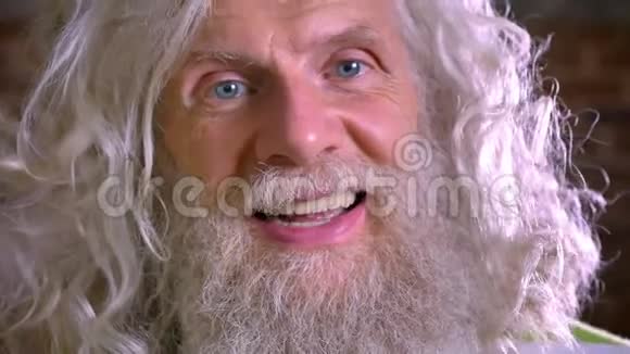 白种人奶奶的特写肖像令人敬畏的长白胡须和头发在镜头前开心地笑着砖头视频的预览图