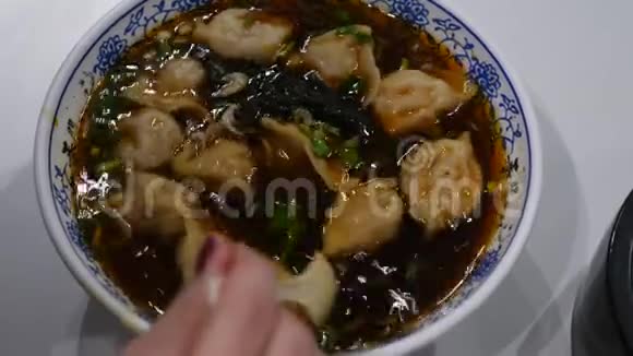 碗里的饺子汤女人用勺子搅拌热食视频的预览图