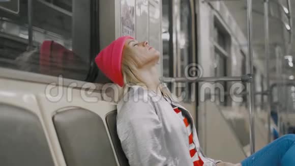这位疲惫迷人的金发女孩正在地下地铁里听音乐打哈欠回家视频的预览图