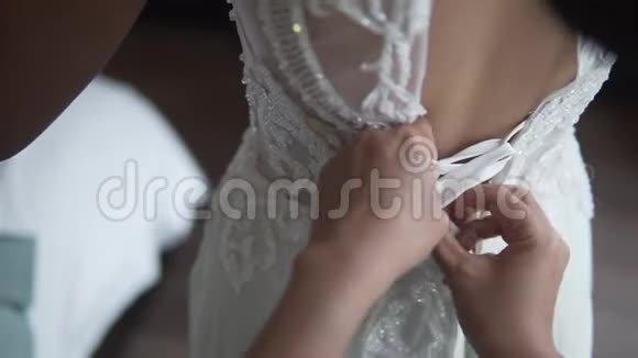 伴娘在清晨用双手系着漂亮的白色婚纱女人支持可爱视频的预览图