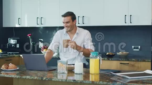 商人在大厨房里看视频惊讶的人看着笔记本电脑视频的预览图