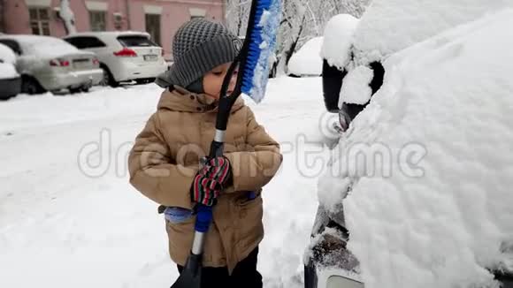 4K小男孩用刷子帮他父亲擦雪车的镜头视频的预览图