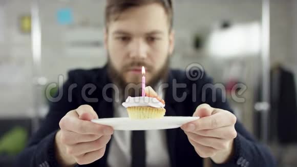 悲伤的商人在办公室里庆祝一个孤独的生日他一个小蛋糕上吹蜡烛小蛋糕蛋糕视频的预览图