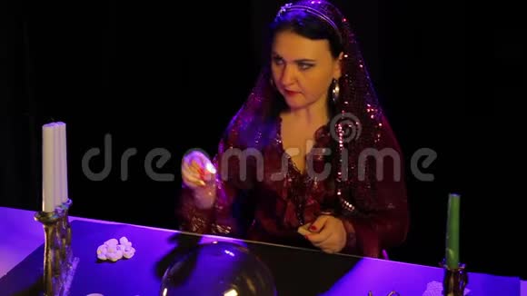在占卜室的桌子上一个穿着红衣服的吉普赛人在雕刻的烛台上点燃蜡烛视频的预览图