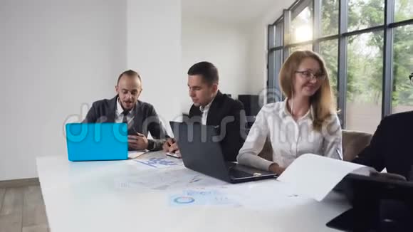 成群结队的人坐在餐桌前讨论一个企业的问题业务小组会议视频的预览图