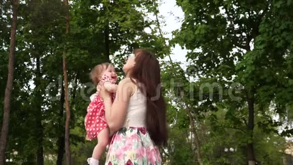 妈妈把女儿抛在空中在公园玩妈妈和宝宝一起散步笑慢动作视频的预览图