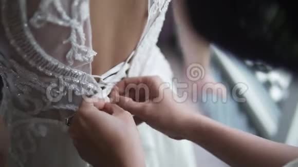 伴娘在清晨用双手系着漂亮的白色婚纱女人支持可爱视频的预览图