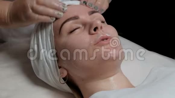 戴透明手套的美容师将客户的颈部脸颊和下巴面霜分发A视频的预览图