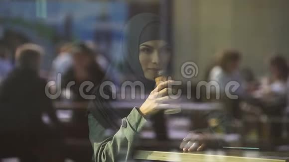 自由穆斯林女士在咖啡馆喝咖啡想着机会微笑视频的预览图