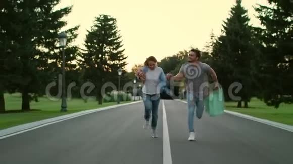 快乐的一对情侣牵着手在夏天公园的路上奔跑视频的预览图