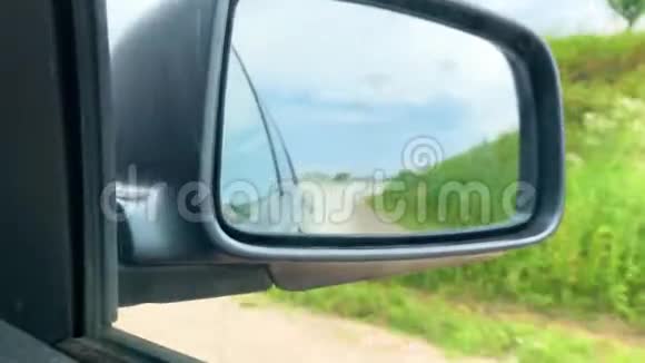 在侧镜下汽车在阳光明媚的一天在村里驶离公路视频的预览图