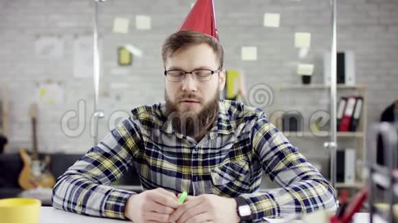 在办公室里度过一个孤独的生日他在一个小蛋糕上吹着蜡烛视频的预览图