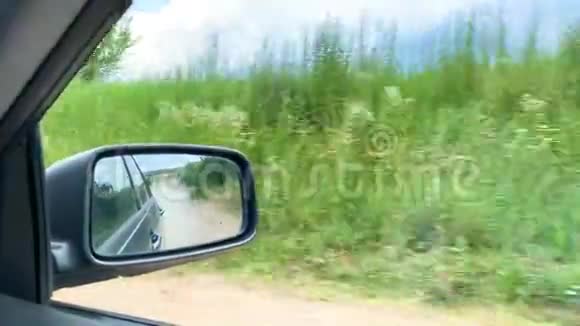 在侧镜下汽车在阳光明媚的一天在村里驶离公路视频的预览图