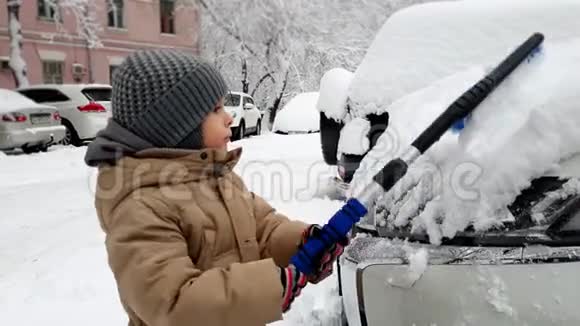 暴雪后幼儿用刷子帮幼儿清洁车从雪中清洁车4k视频视频的预览图