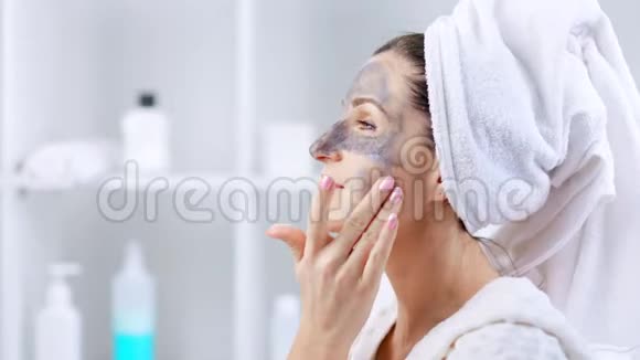 头上戴白毛巾脸上戴化妆面具的年轻女子视频的预览图