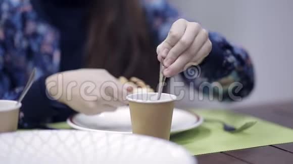 女孩用手在一个纸杯里搅拌着茶视频的预览图