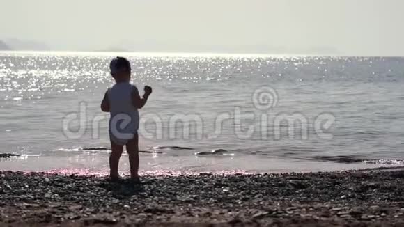一个小男孩背对着镜头向海里扔一颗鹅卵石视频的预览图