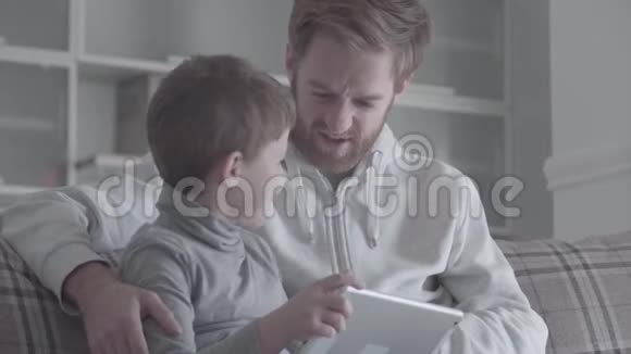 小笑脸男孩抓住父亲的鼻子拉着它两人都在笑父亲之间的友好关系视频的预览图