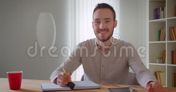 年轻英俊的白种人男学生正在学习用平板电脑看着镜头微笑的特写镜头视频的预览图
