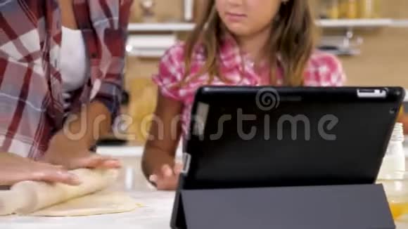母女俩在厨房做饭看着一台数码平板电脑做菜谱视频的预览图